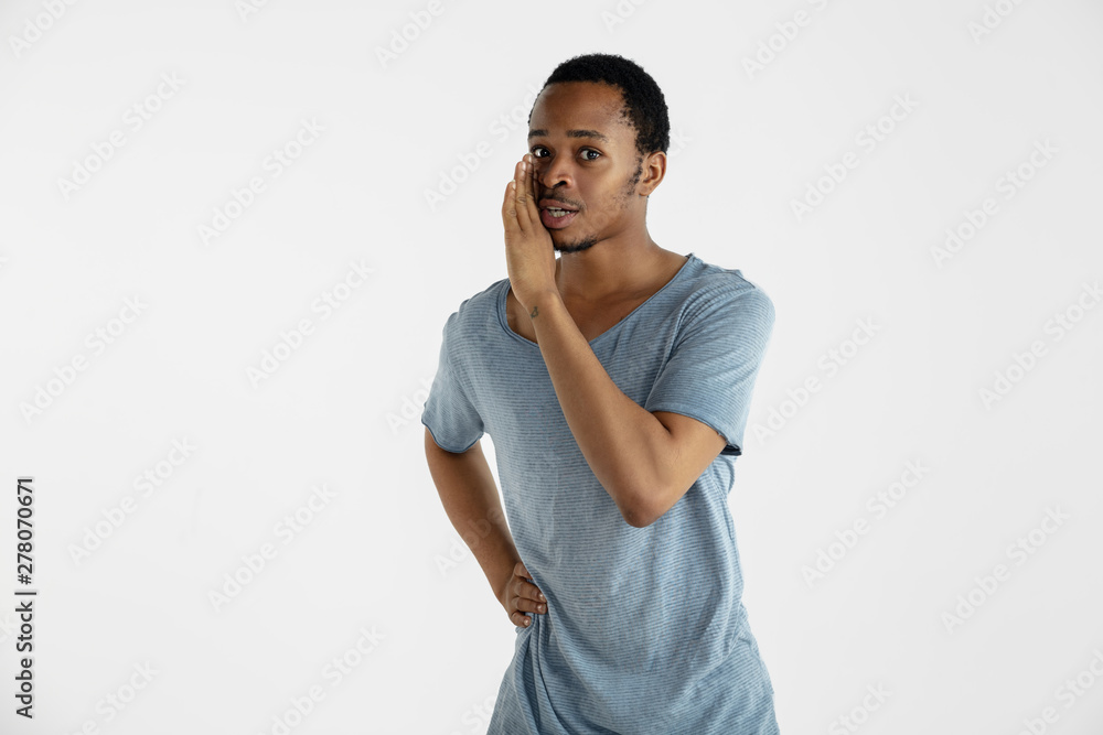 Beautiful male half-length portrait isolated on white studio background. Young emotional african-american man in blue shirt. Facial expression, human emotions, ad concept. Whispering a secret, smiling Beautiful male half-length portrait isolated on white studio background. Young emotional african-american man in blue shirt. Facial expression, human emotions, ad concept. Whispering a secret, smiling