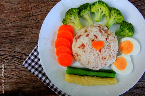 Clean food have brown rice, broccoli,carrot,Lentils,Baby corn,and egg in white disc on the wood table, healthy or vegetarian food concept Top view. 