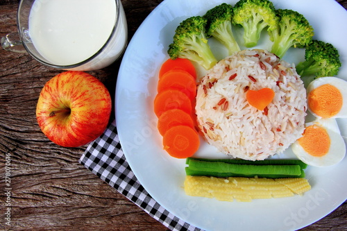 Clean food have brown rice,milk,apple broccoli,carrot,Lentils,Baby corn,and egg in white disc on the wood table, healthy or vegetarian food concept Top view. 