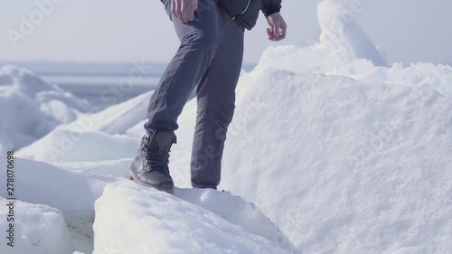 Young bearded handsome man in warm jacket,hat and boots climbling the glacier. Amazing nature of a snowy glacier. The polar explorer on the block of ice. photo