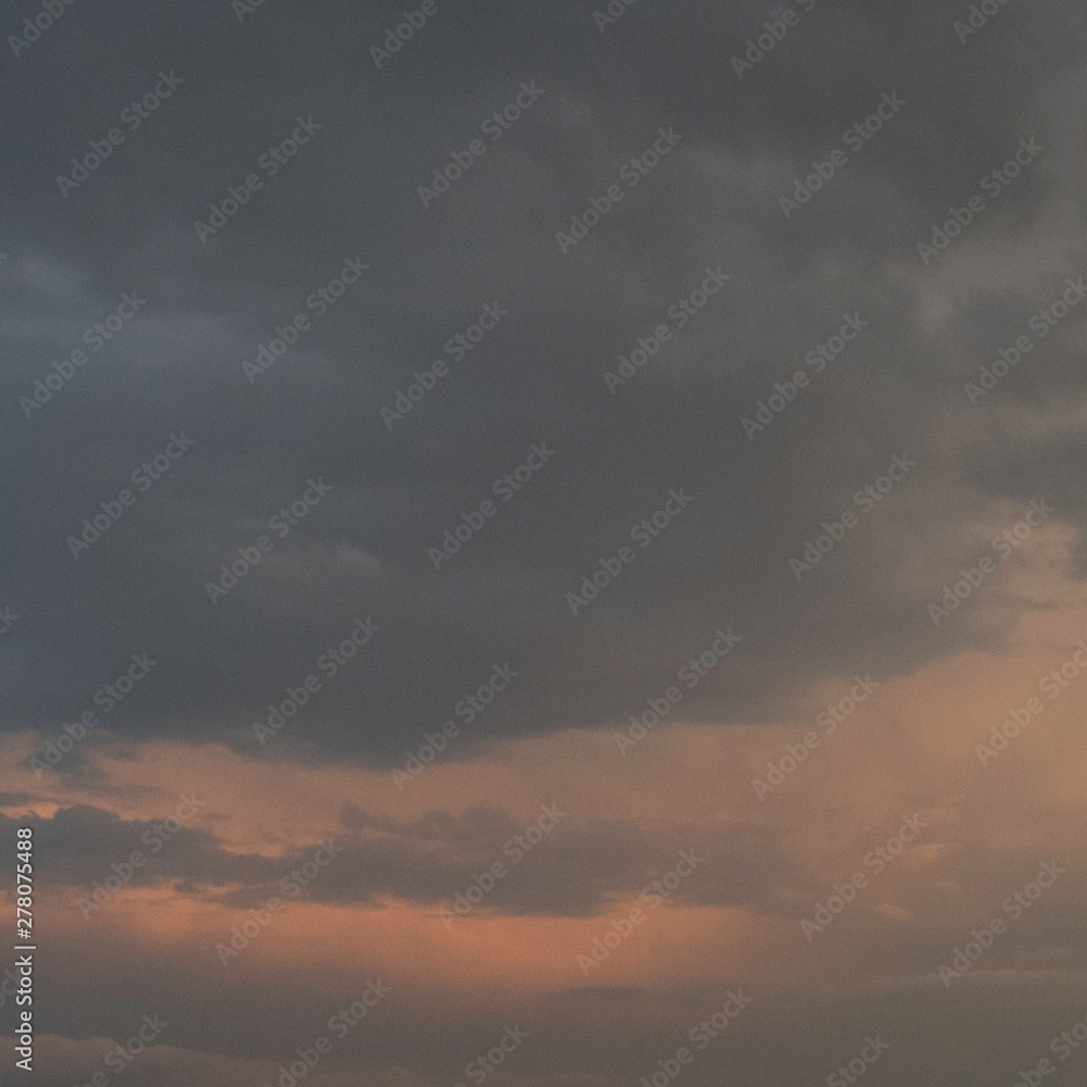 Dramatic dark clouds in the sky with orange sunlight color on the clouds.
