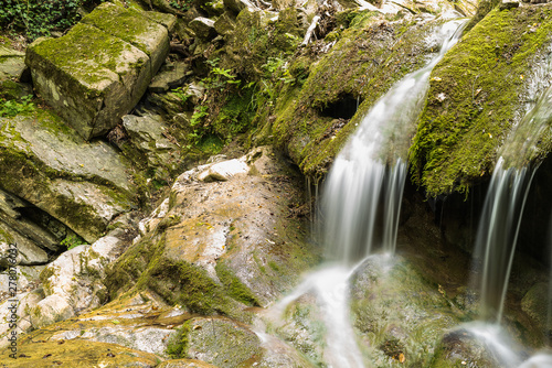small waterfall in a dense Italian forest with lush vegetation. Silk effect water