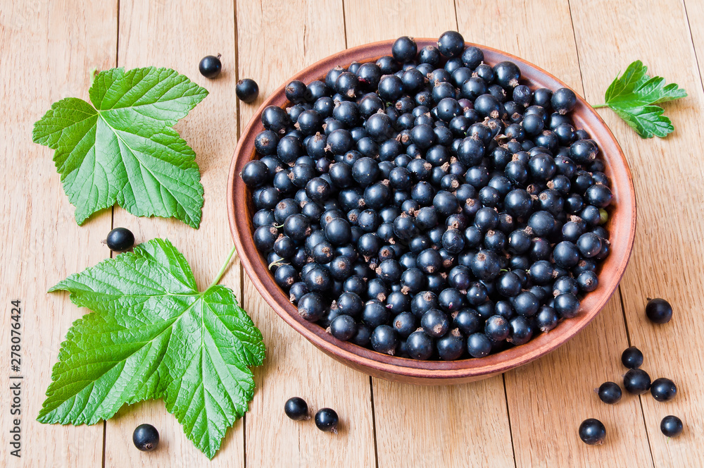 Currant. Fresh berries of black currant on a plate on a wooden table Currant. Fresh berries of black currant on a plate on a wooden table