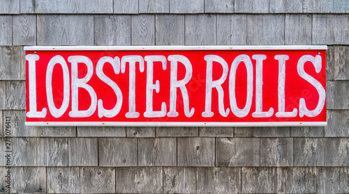 Rustic hand painted seafood sign on a wall of weathered shingles.