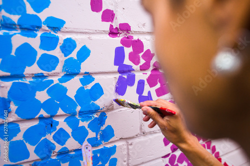 The artist draws on a brick wall.