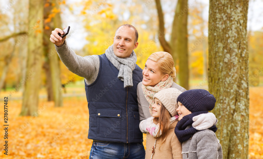 Fototapeta premium family, childhood, season, technology and people concept - happy family taking selfie with smartphone in autumn park