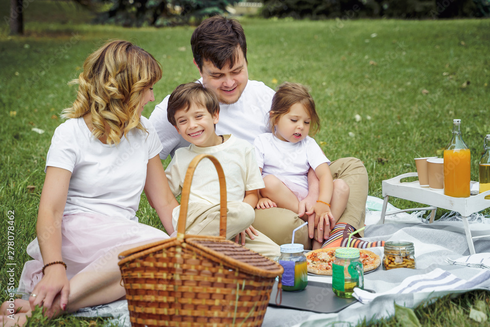 Happy family with kids resting on the grass during a picnic. Happiness and harmony in family life. Happy family with kids resting on the grass during a picnic. Happiness and harmony in family life.