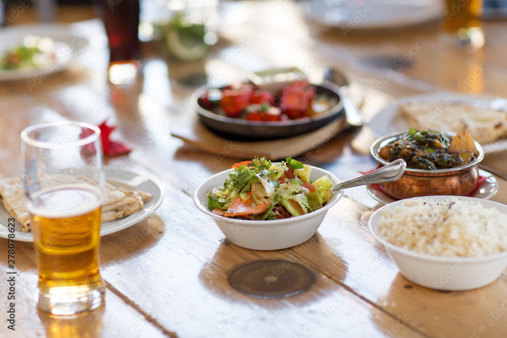 food, south asian cuisine, culinary and cooking concept - vegetable salad in bowl and various dishes on table of indian restaurant food, south asian cuisine, culinary and cooking concept - vegetable salad in bowl and various dishes on table of indian restaurant