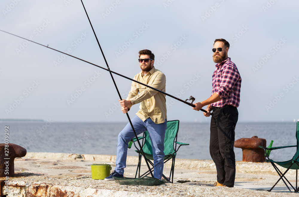 leisure and people concept - male friends with fishing rods on pier at sea leisure and people concept - male friends with fishing rods on pier at sea