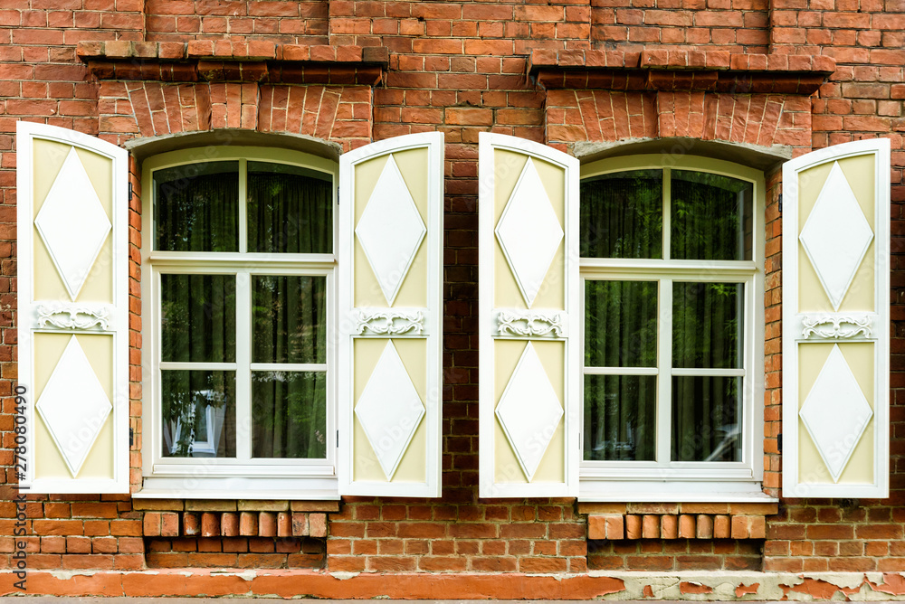 two windows with the wooden carved architrave in the old wooden house in the old Russian town.