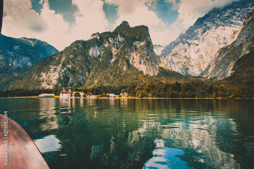 View to St. Bartholomew's Church and mountains from a boat on the Koenigssee lake, Germany