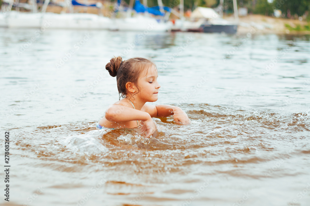Little happy girl plays with water and splashes of water in the sea Little happy girl plays with water and splashes of water in the sea