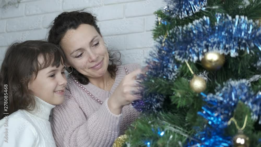 Family decorates the Christmas tree. Preparing for Christmas. Mother and daughter decorate the Christmas tree. Family decorates the Christmas tree. Preparing for Christmas. Mother and daughter decorate the Christmas tree.