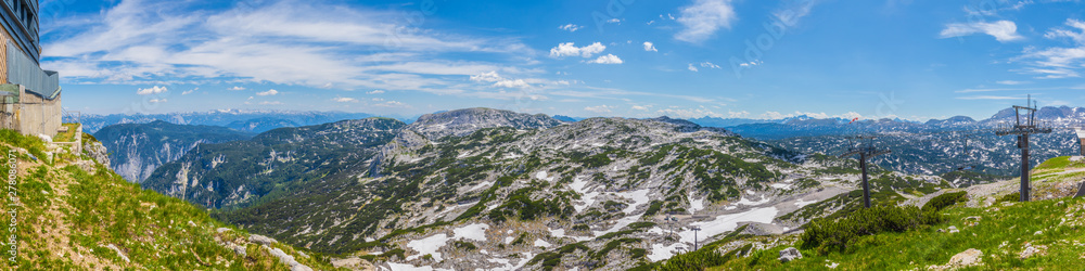Panoramic view of the European Alps from Dachstein Krippenstein, Austria. Cable car pillars, rocky hills and snowy mountains on the horizon. Travel, wanderlust concept.