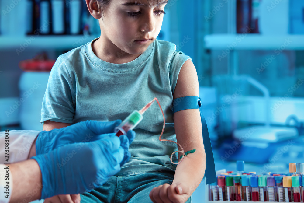 technician making blood tests on a young boy in the laboratory of blood