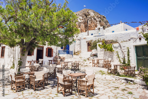 Fototapeta Naklejka Na Ścianę i Meble -  Traditional greek street with flowers and cafe tables in Amorgos island, Cyclades, Greece