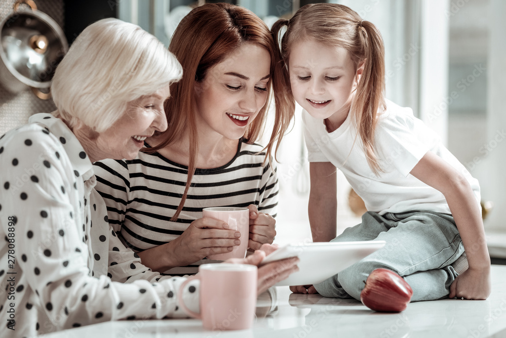 Three generations smiling and looking at the screen of modern tablet Three generations smiling and looking at the screen of modern tablet