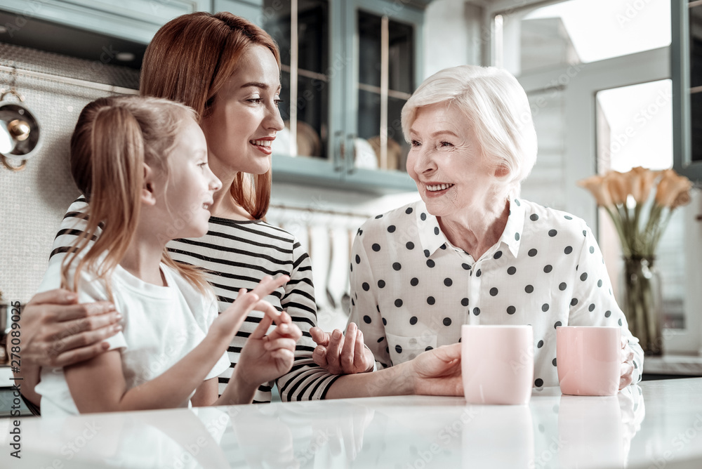 Friendly women of one family sitting at the kitchen table and talking Friendly women of one family sitting at the kitchen table and talking