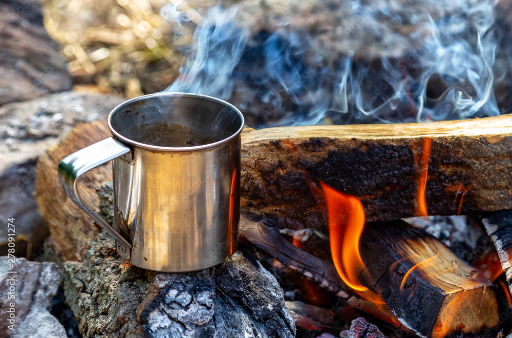 steel cup on an open fire in nature. Cooking on fire. Camping in summer. steel cup on an open fire in nature. Cooking on fire. Camping in summer.
