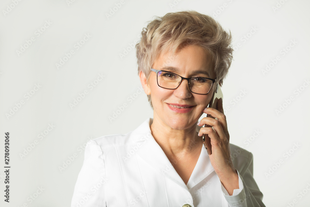 portrait of an adult woman with a short haircut wearing glasses in a white jacket on a white background makes phone calls