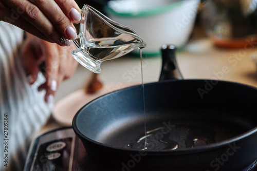 Vegetable oil pouring from a bottle into a frying pan.
