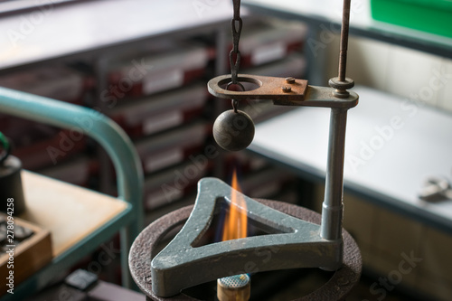 Gravesande experiment: iron ball is heated by a hot flame and will not fit in the ring above after heating. Physics experiment showing the principle of expansion. photo