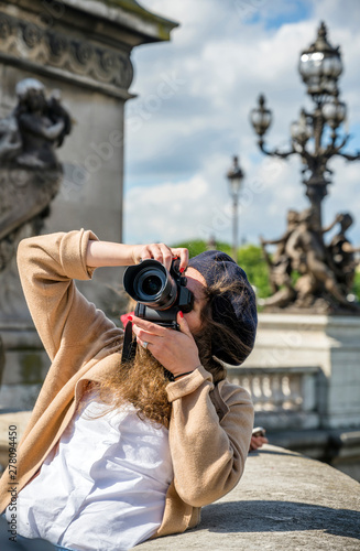 A girl photographs the sights of the city on a professional camera