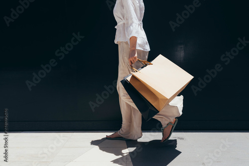Unrecognisable stylish woman holding shopping bags and walking outdoors.