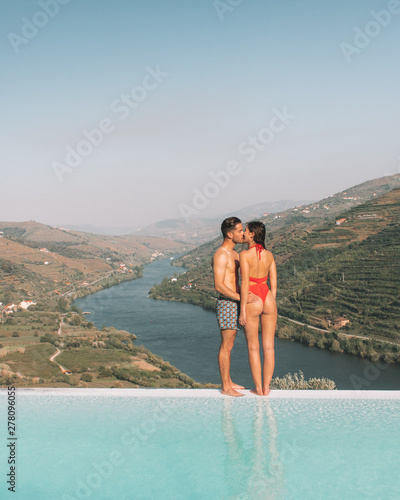 man and woman kissing on the edge of infinity pool during daytime