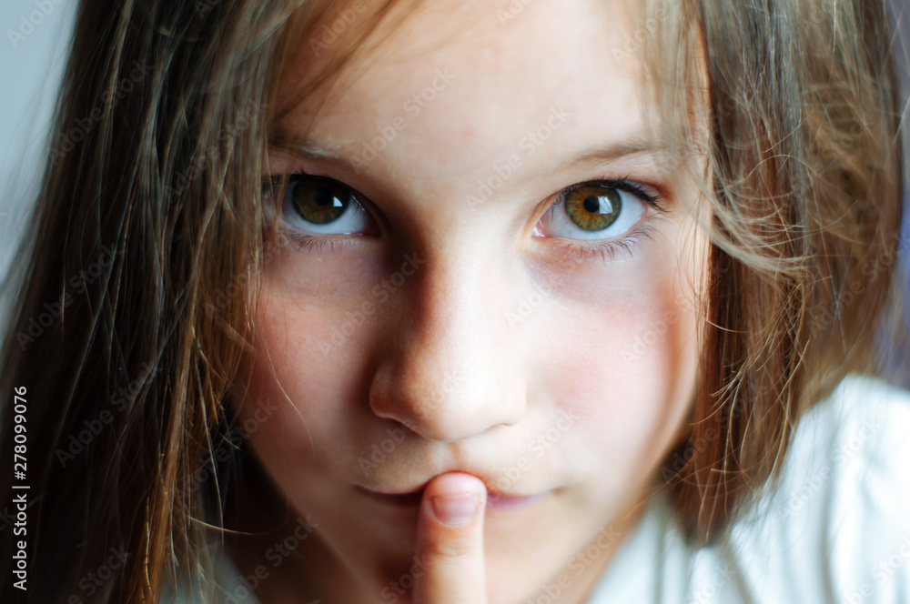 Beautiful young girl with long hair puts a finger in her mouth, close portrait Beautiful young girl with long hair puts a finger in her mouth, close portrait
