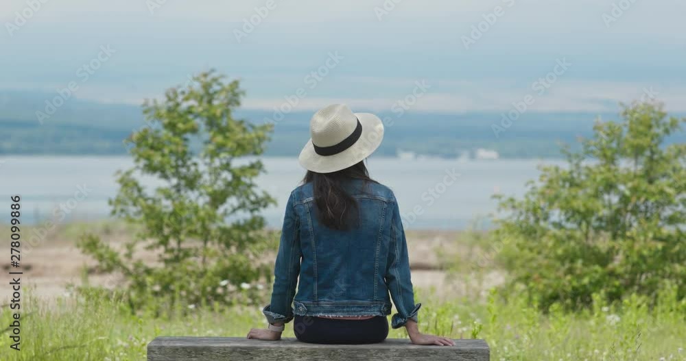 Woman look around the landscape and sit on the wooden bench Woman look around the landscape and sit on the wooden bench