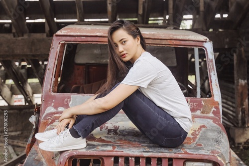 Young woman sitting on hood of rusted truck photo