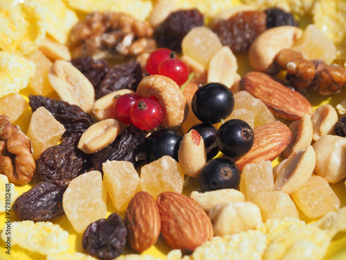 Tasty and beautiful dish is with black and red currant berries, corn flakes, candied fruits and assorted nuts on the background. Prepare a delicious and healthy dessert for Breakfast for children.