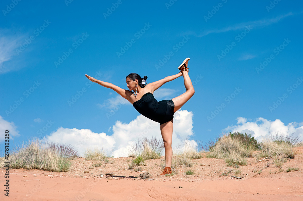 Native American woman in yoga pose in the red desert of New Mexico. 
