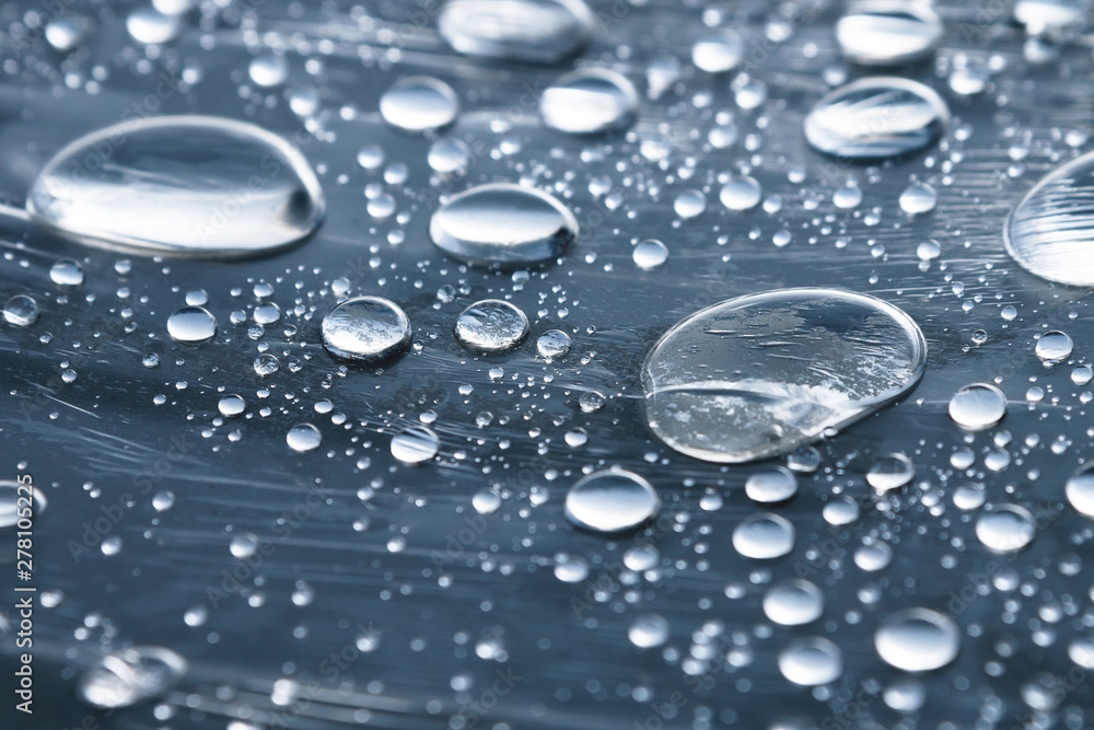 Close-up of raindrops of different sizes on the surface covered with cling film. Moisture weather and humidity concept Close-up of raindrops of different sizes on the surface covered with cling film. Moisture weather and humidity concept