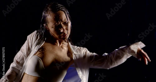 Wallpaper Mural young wet female dancer is moving hands under rain in darkness, medium shot Torontodigital.ca
