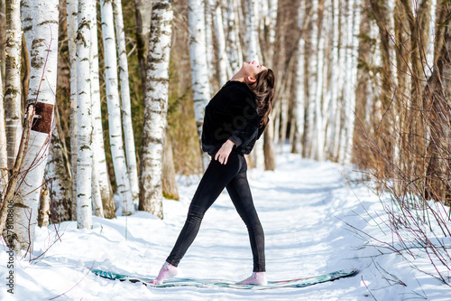 Yoga in the snow. Girl practicing yoga in the Park. Time of year winter. Snow-covered trees.