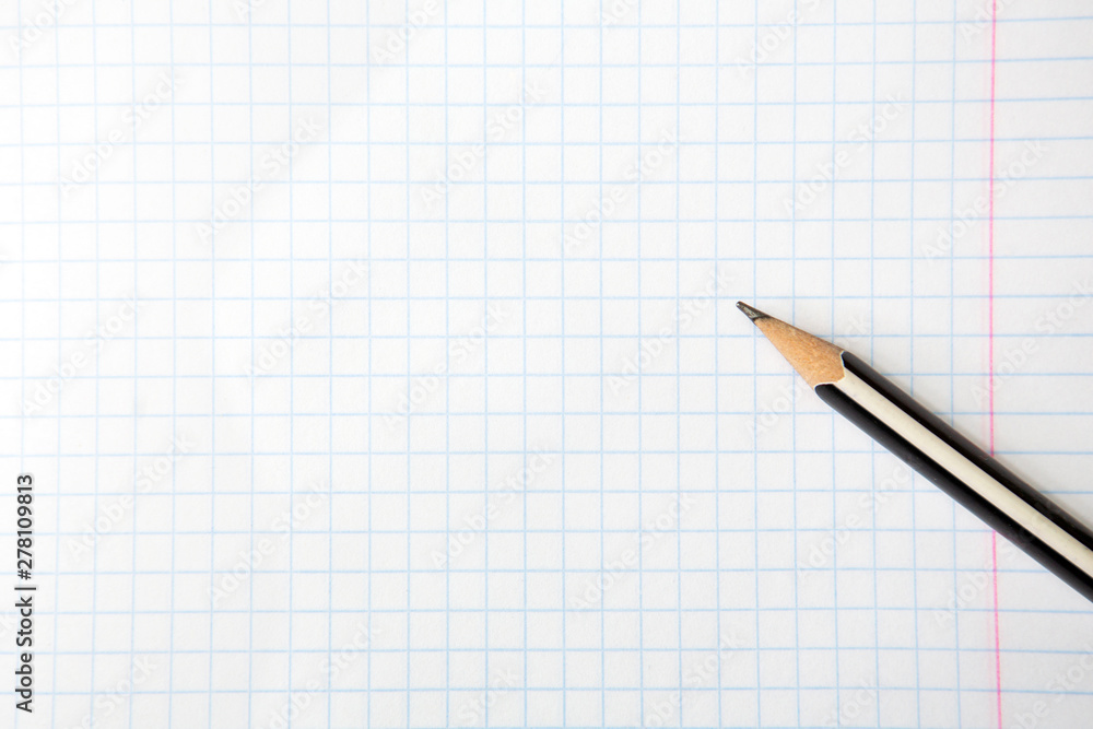 A pencil on a squared notebook. Copy space. Close-up. A pencil on a squared notebook. Copy space. Close-up.