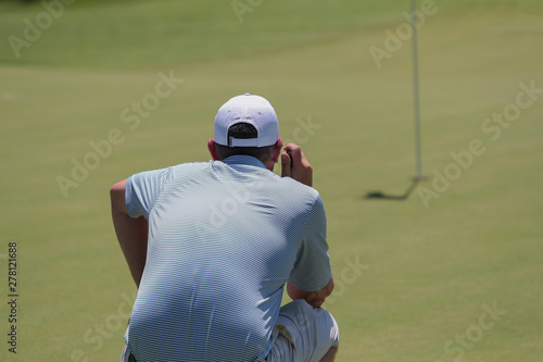 A golfer sizes up the slope of the putting surface during a tournament