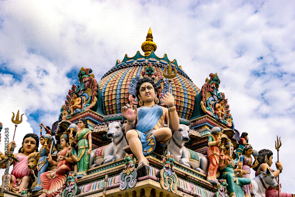 Colourful sculptures of expressive hindu deities above a temple.