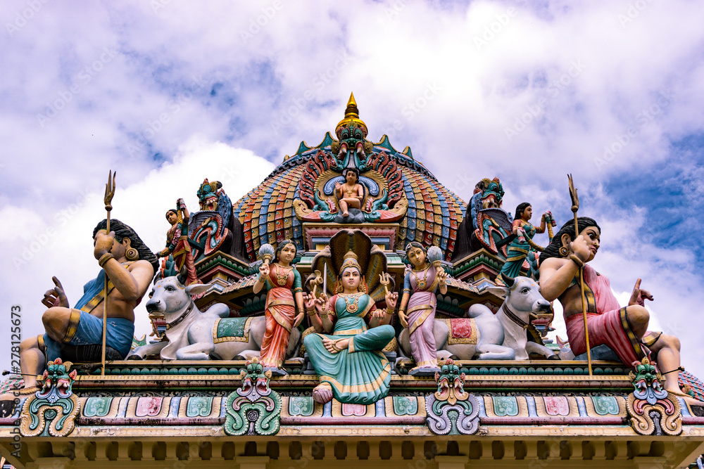 Naklejka premium Colourful sculptures of expressive hindu deities above a temple.