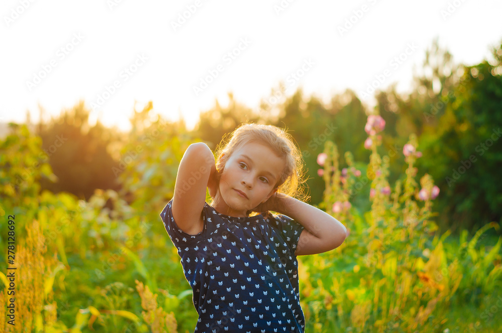 little adorable girl in a field at sunset spread her arms, enjoying little adorable girl in a field at sunset spread her arms, enjoying