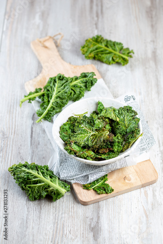 Homemade Green Kale Chips on vintage newspapper, white background