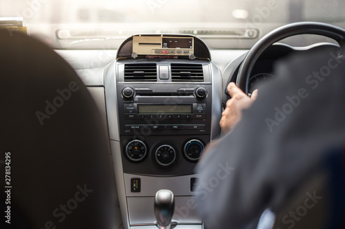 Men's hand holding the steering wheel and meter in taxi with sunlight