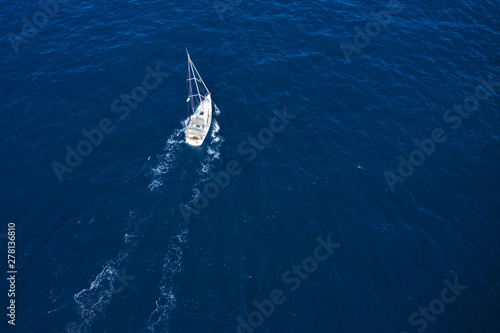 View from above, stunning aerial view of a sailboat sailing on a blue sea. Emerald coast (Costa Smeralda), Sardinia, Italy.