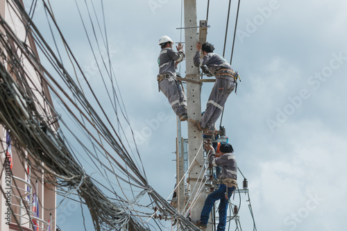 Electricians repairing,electricians repairing wire on electric power pole, power linesman climb the pole.It's a dangerous job.