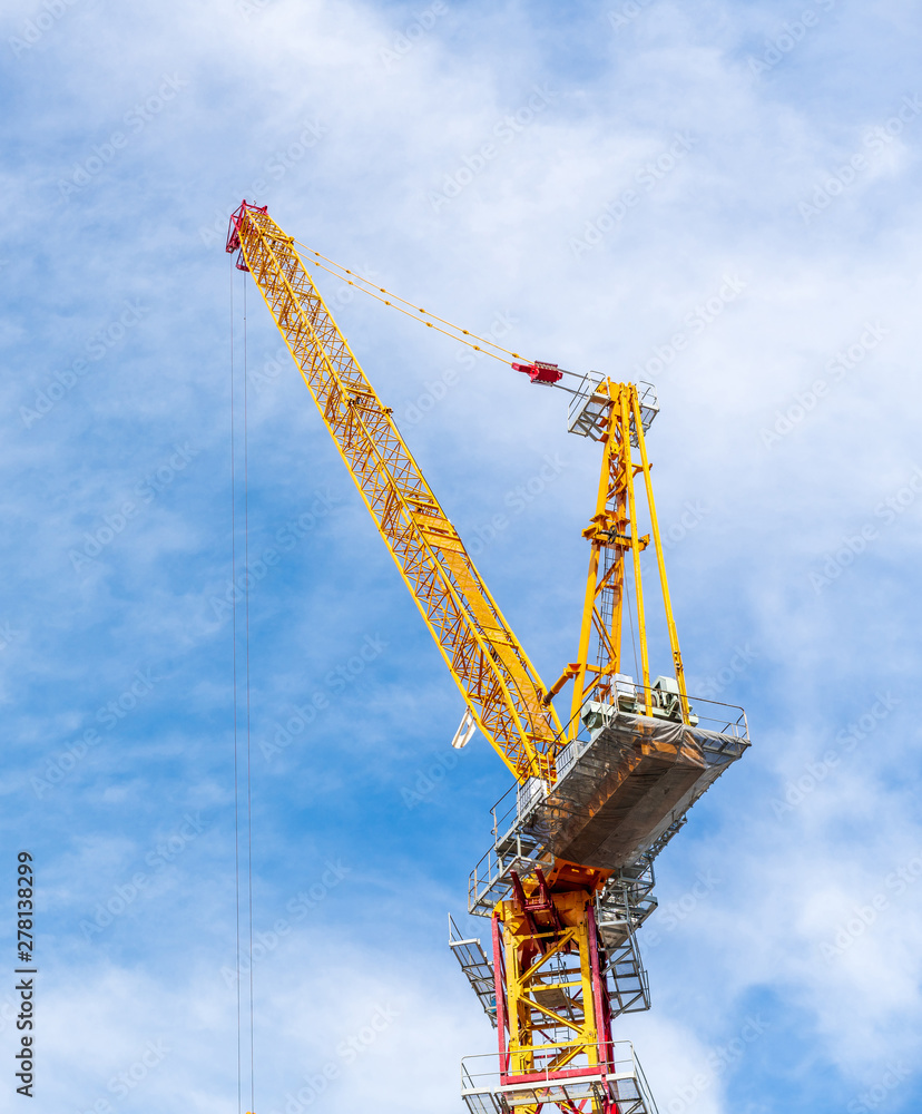 Crane working in construction site with cloud and blue sky in background in Bangkok, Thailand.