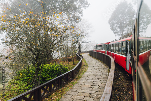 Moving red trains in Alishan Forest Railway stop with motion blur trees outside in Alishan, Taiwan.