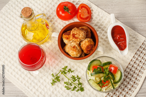 Fried meat cutlets in bowl, salad, glass of wine and bottle with sunflower oil