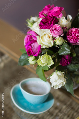 blue ceramic cup with coffee and roses blowers on glass table
